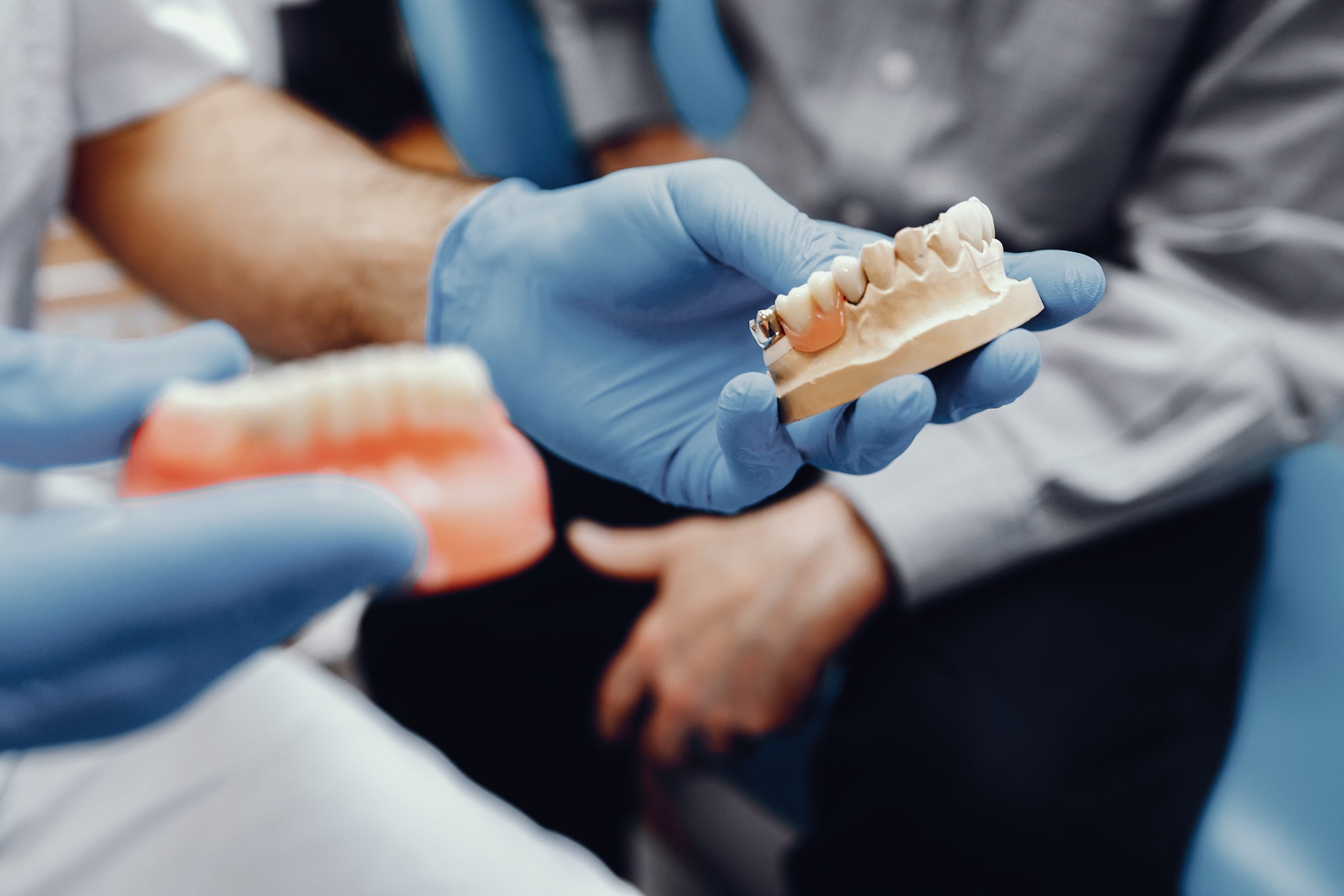 Plastic jaw in the dentist's office. The doctor holds in the hands of dental implants.